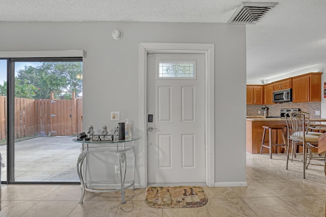 foyer featuring light tile patterned floors, visible vents, and a textured ceiling