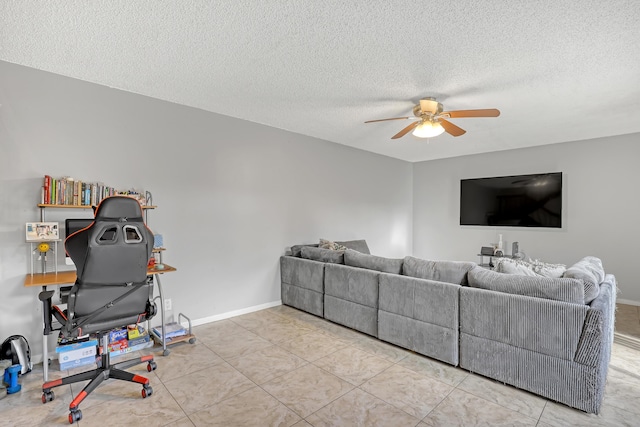 living area with a ceiling fan, a textured ceiling, and baseboards