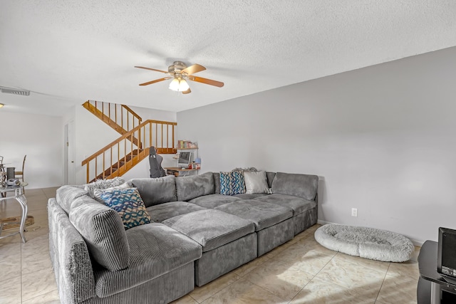 living area featuring a ceiling fan, visible vents, a textured ceiling, and stairs