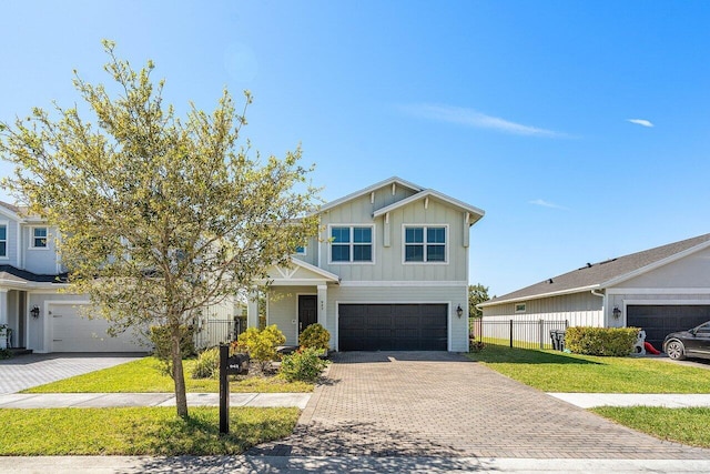 craftsman-style house with board and batten siding, an attached garage, decorative driveway, and fence