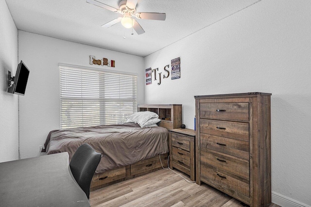 bedroom with light wood-style floors, ceiling fan, and a textured ceiling