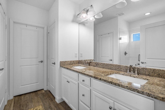 full bath with a shower stall, wood finished floors, visible vents, and a sink