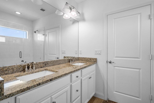 bathroom featuring double vanity, visible vents, a shower stall, and a sink