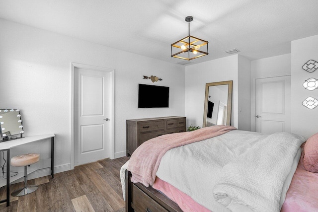 bedroom with visible vents, baseboards, an inviting chandelier, and wood finished floors