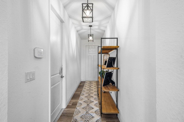 hall with wood finished floors, baseboards, and a textured wall