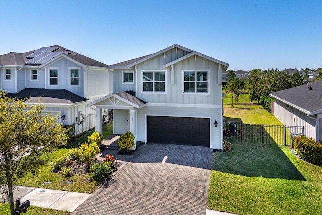 view of front of house with a front lawn, decorative driveway, fence, board and batten siding, and an attached garage