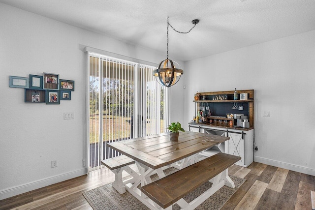 dining space featuring a notable chandelier, baseboards, light wood finished floors, and a textured ceiling