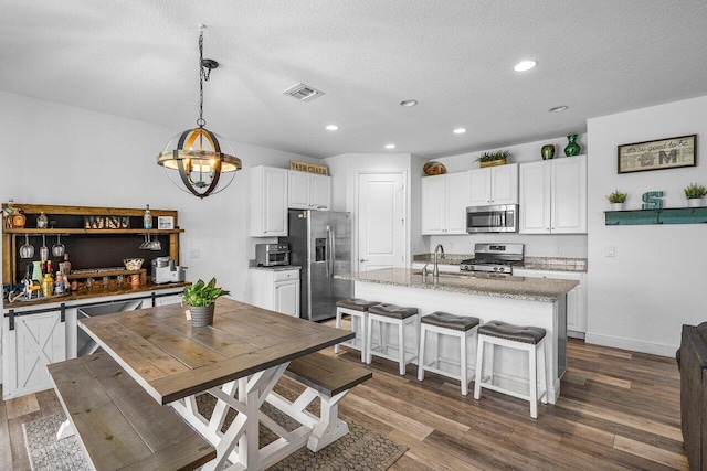 kitchen with visible vents, white cabinetry, stainless steel appliances, and dark wood-style flooring