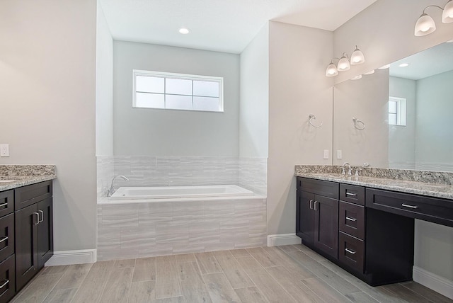 bathroom featuring vanity, tiled bath, and a wealth of natural light