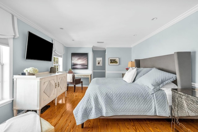 bedroom featuring ornamental molding, light wood-type flooring, and baseboards