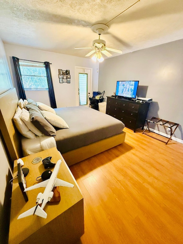 bedroom featuring ceiling fan, wood-type flooring, and a textured ceiling