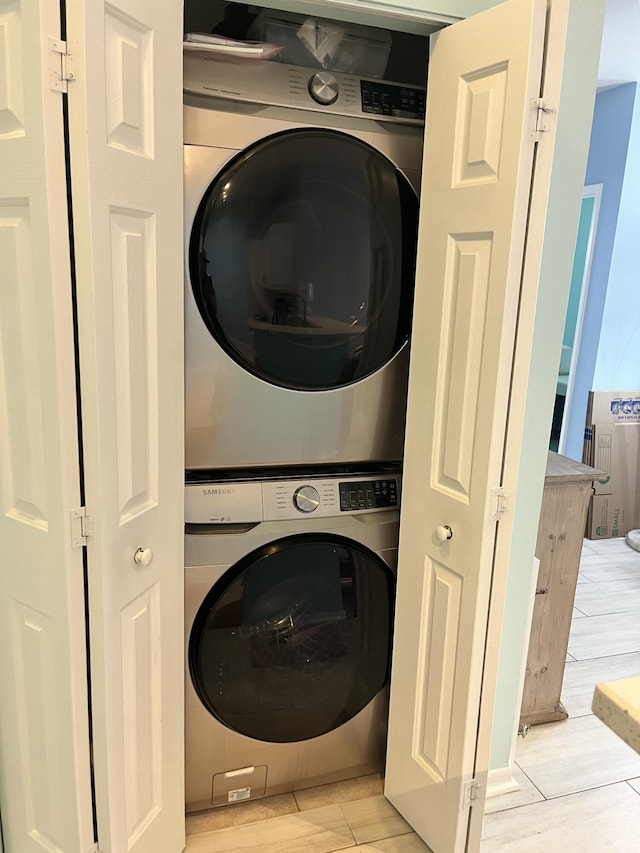 washroom with light hardwood / wood-style floors and stacked washer and clothes dryer