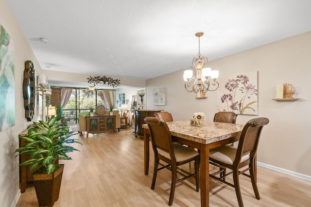 dining area featuring a textured ceiling, a chandelier, and light hardwood / wood-style floors