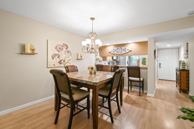 dining space featuring light wood-type flooring and a chandelier