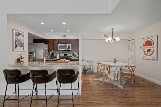 kitchen with sink, appliances with stainless steel finishes, backsplash, hanging light fixtures, and dark brown cabinets