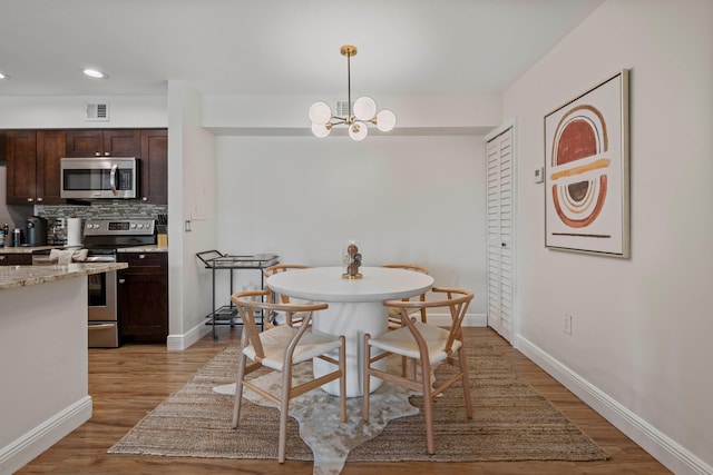 dining room with an inviting chandelier and light hardwood / wood-style flooring