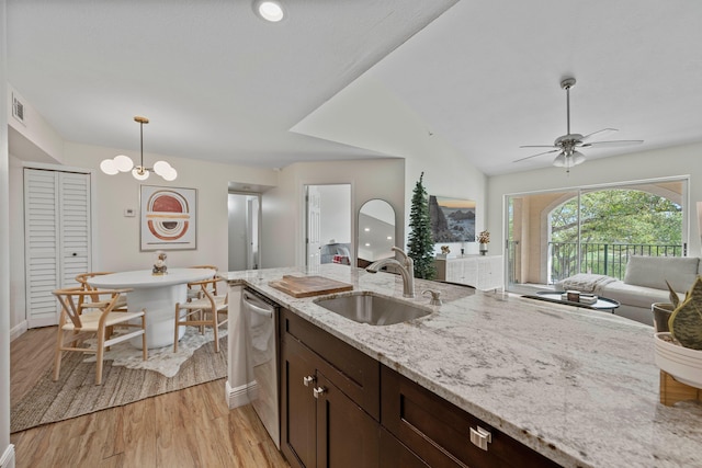 kitchen with dark brown cabinetry, sink, light stone counters, decorative light fixtures, and light hardwood / wood-style floors