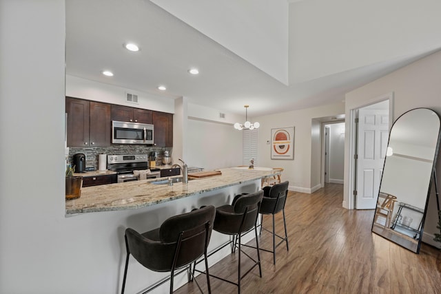 kitchen featuring pendant lighting, sink, a kitchen bar, dark brown cabinetry, and stainless steel appliances