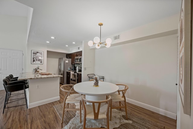 dining area featuring dark hardwood / wood-style floors, sink, and a notable chandelier