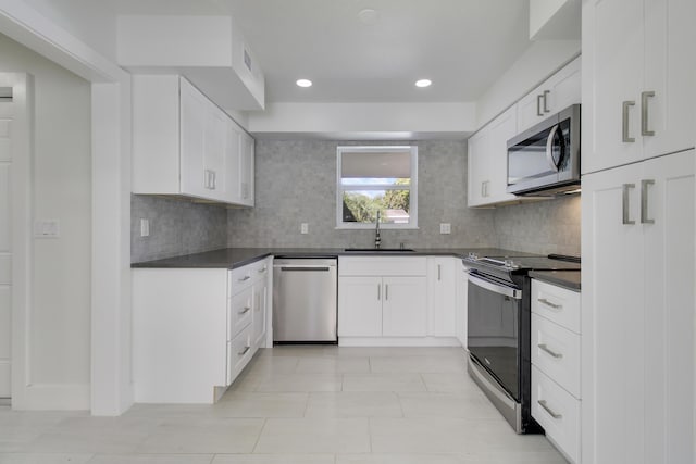 kitchen featuring dark countertops, appliances with stainless steel finishes, white cabinets, and a sink