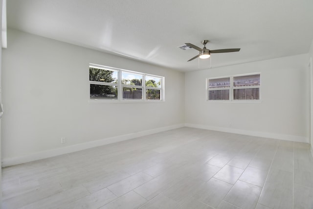 spare room featuring ceiling fan, visible vents, and baseboards