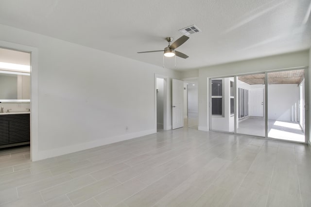 unfurnished room with a ceiling fan, visible vents, a textured ceiling, and baseboards