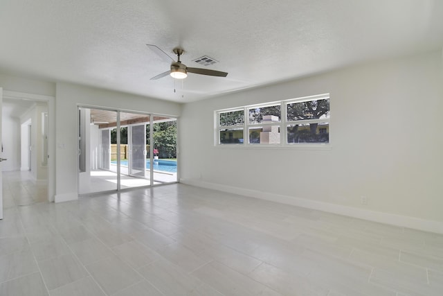 unfurnished room with visible vents, ceiling fan, a textured ceiling, and baseboards