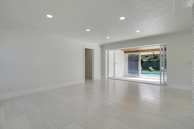 empty room with a textured ceiling, recessed lighting, and baseboards