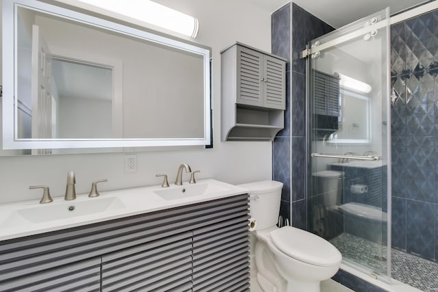 full bathroom with toilet, a shower stall, double vanity, and a sink