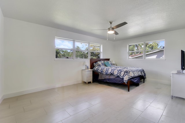 bedroom featuring a ceiling fan, multiple windows, baseboards, and a textured ceiling