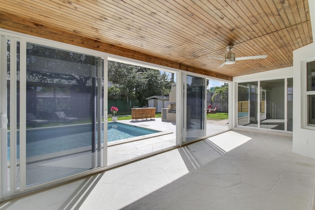 unfurnished sunroom featuring wood ceiling and a ceiling fan