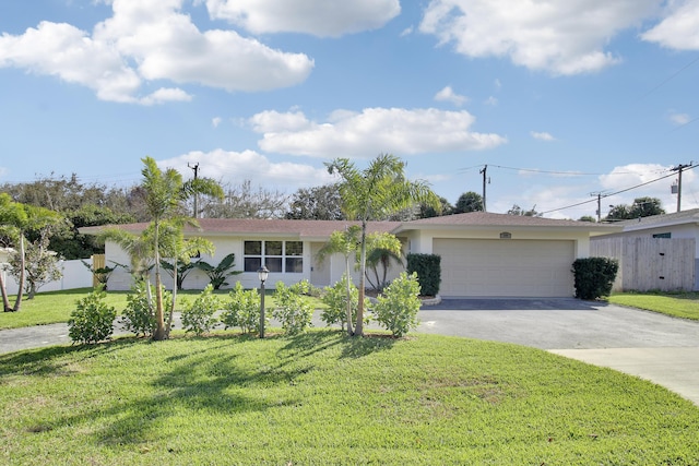 ranch-style house featuring driveway, a garage, fence, a front lawn, and stucco siding