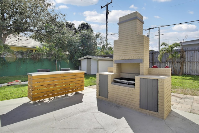 view of patio featuring a brick fireplace, fence, a storage unit, and an outdoor structure