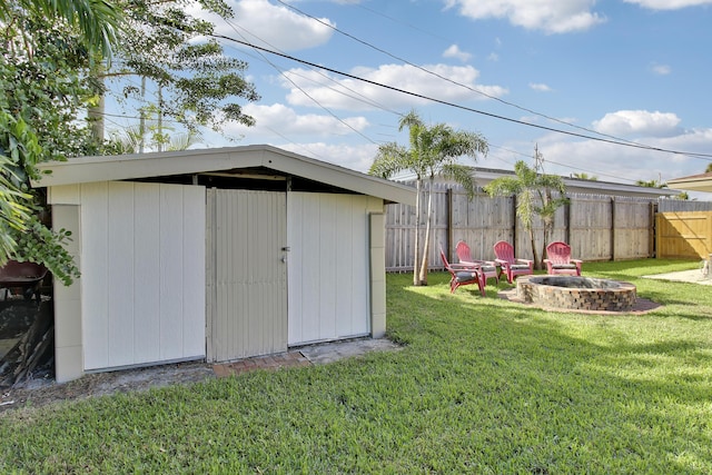 view of shed with fence and a fire pit