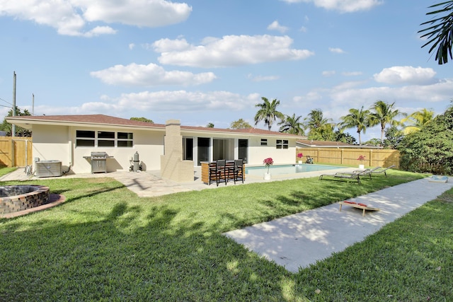 back of house featuring an outdoor fire pit, fence, a yard, a fenced in pool, and a patio area