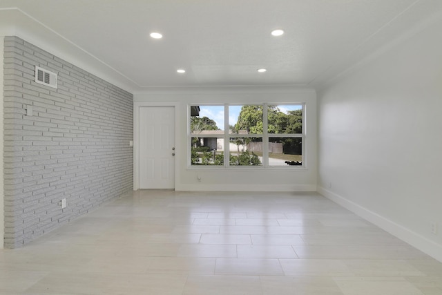 spare room with brick wall, recessed lighting, visible vents, and baseboards