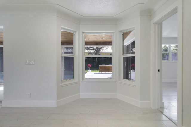 empty room with a textured ceiling and baseboards