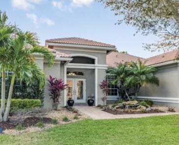 exterior space featuring french doors, a tile roof, a lawn, and stucco siding