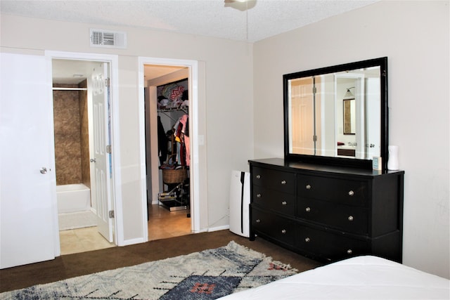 bedroom featuring ensuite bath, a spacious closet, a textured ceiling, carpet flooring, and a closet