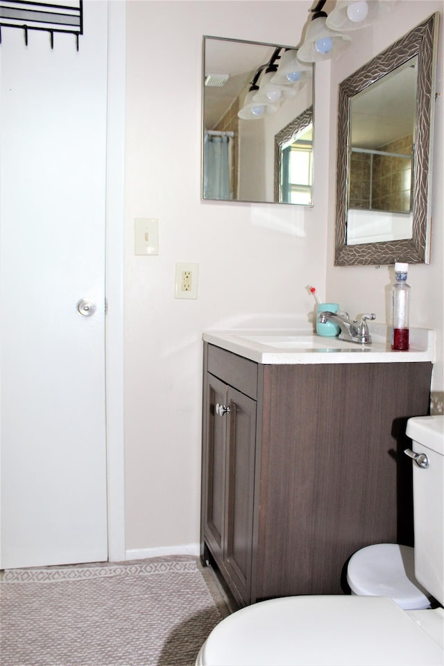 bathroom featuring vanity, walk in shower, and toilet