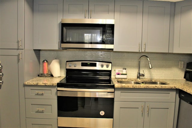 kitchen featuring light stone countertops, appliances with stainless steel finishes, sink, and gray cabinetry