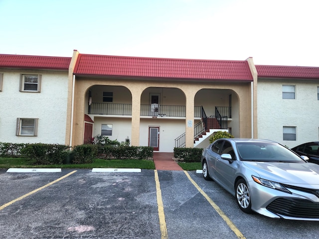 view of property featuring uncovered parking and stairway