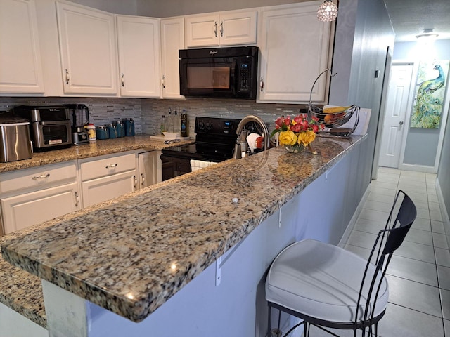 kitchen with light tile patterned floors, backsplash, white cabinets, and black appliances