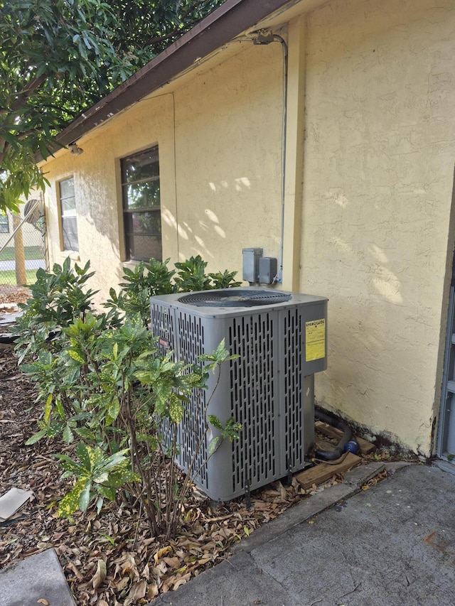 exterior details with fence, cooling unit, and stucco siding