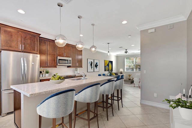 kitchen with appliances with stainless steel finishes, pendant lighting, a sink, and an island with sink