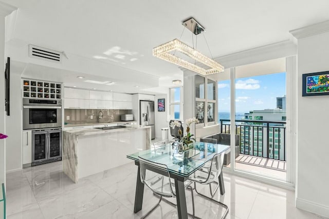 dining space featuring beverage cooler, visible vents, baseboards, a water view, and marble finish floor