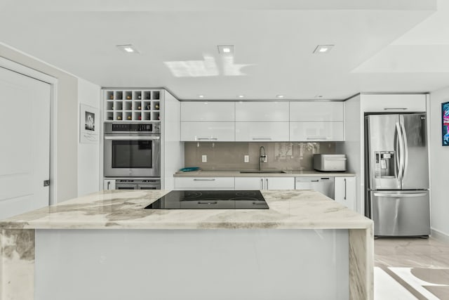 kitchen with stainless steel appliances, white cabinetry, a sink, and modern cabinets