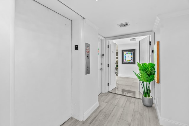 hall with ornamental molding, elevator, visible vents, and baseboards