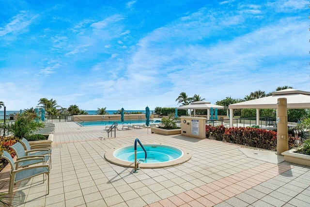 community pool featuring a hot tub, fence, a patio, and a gazebo