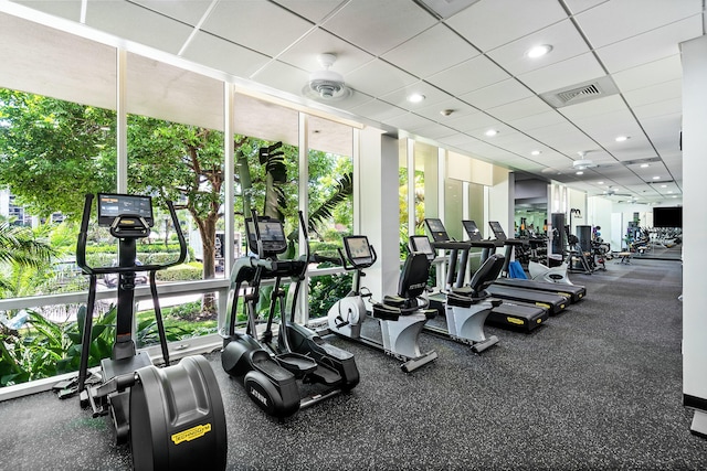 gym with a wall of windows, recessed lighting, visible vents, and a drop ceiling